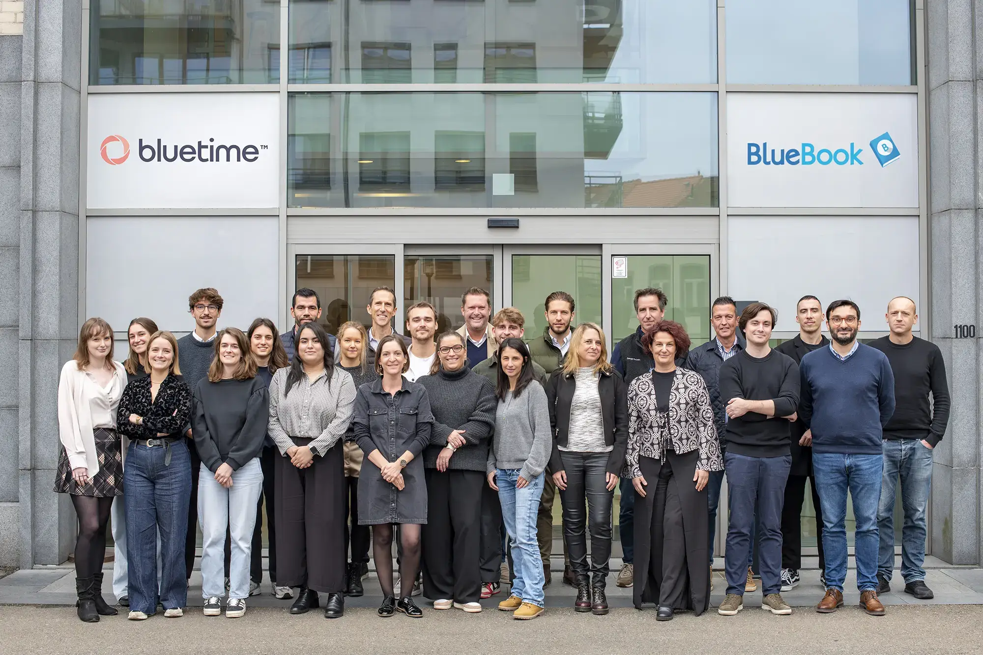 Équipe Bluetime debout devant la façade des bureaux