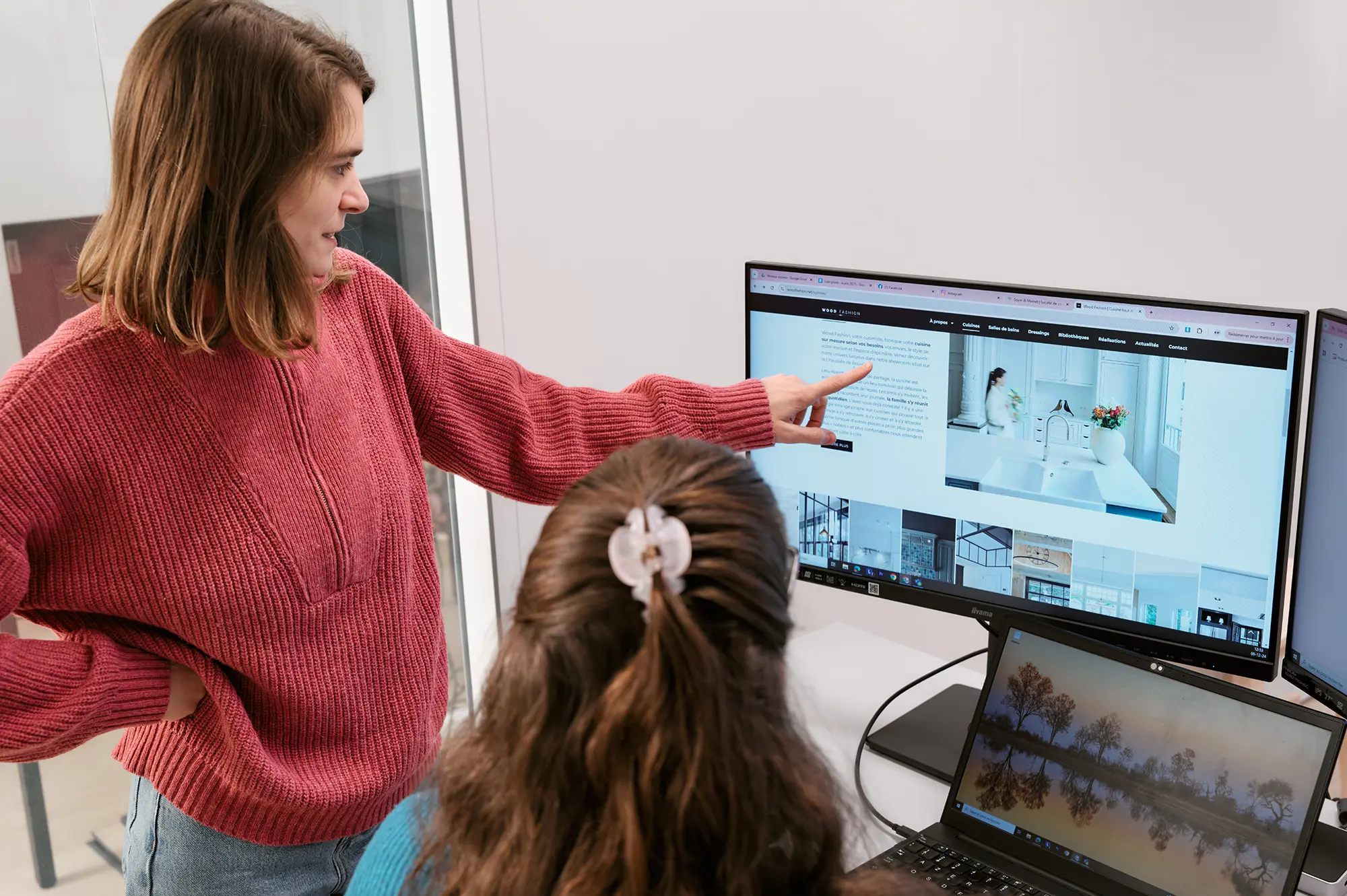A project manager shows a client project to her colleague on a computer screen
