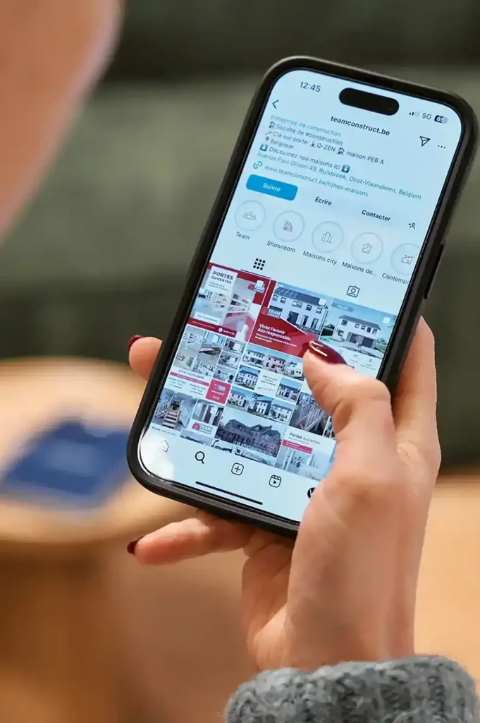 Zoom sur une main tenant un smartphone affichant un profil Instagram
