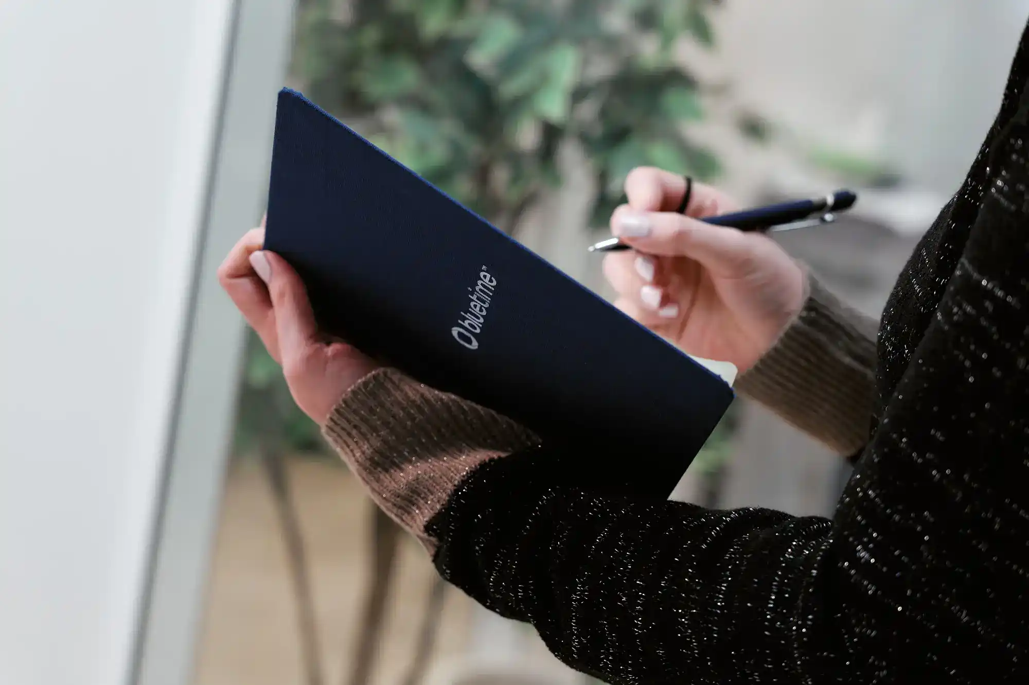 Personne tenant un carnet bleu au logo «&nbsp;Bluetime&nbsp;» et un stylo