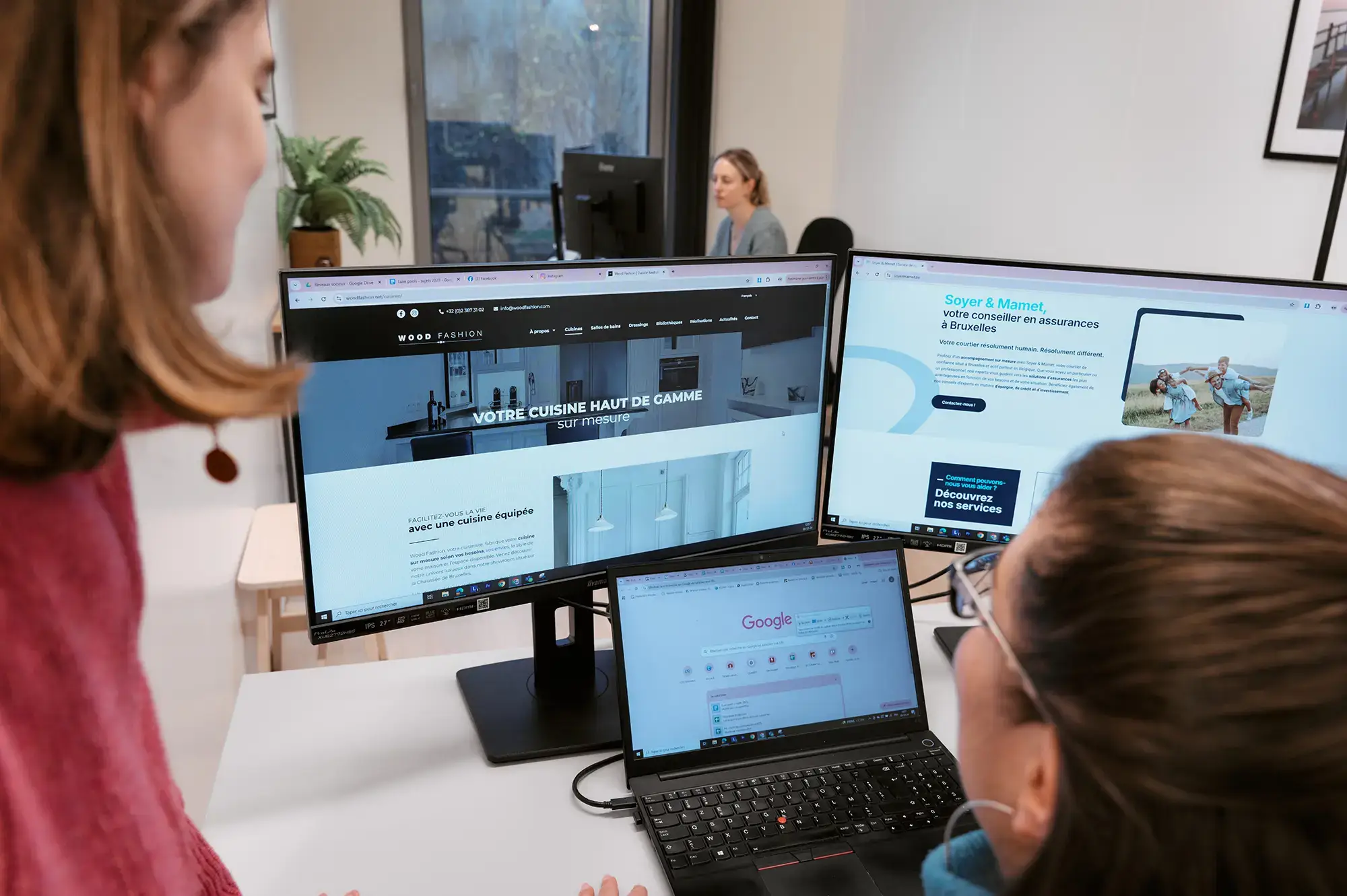 Deux collègues analysent un site sur trois écrans d’ordinateur, une autre travaille en arrière-plan