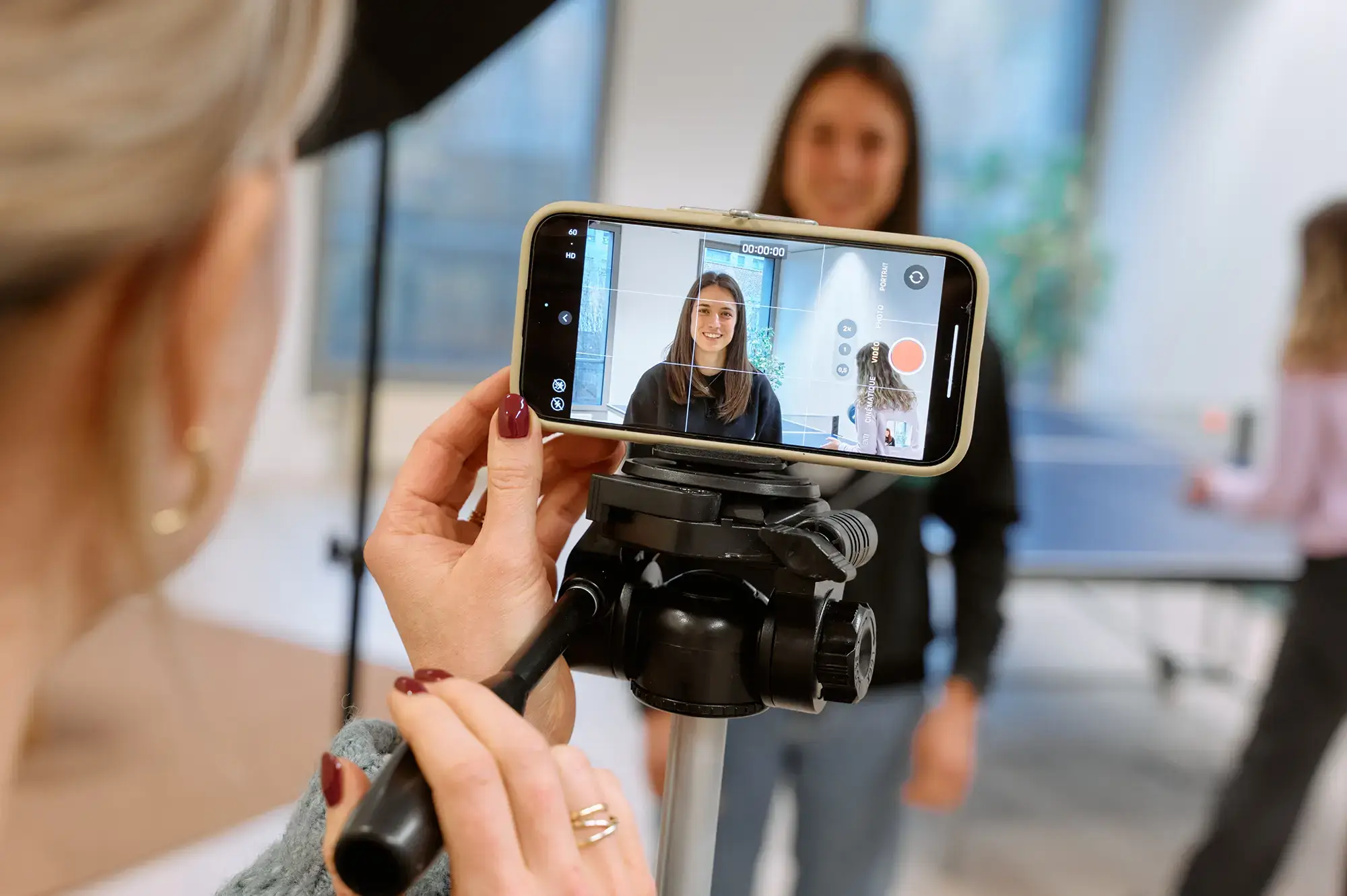 Two colleagues are filming a video with a smartphone on a tripod